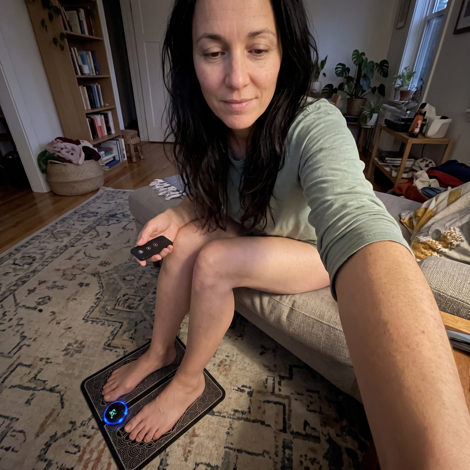 Priya seated in her lounge with the black remote